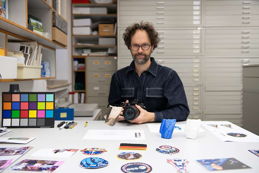 Andres Galeano at his desk in the archive. He is holding a camera in his hands.